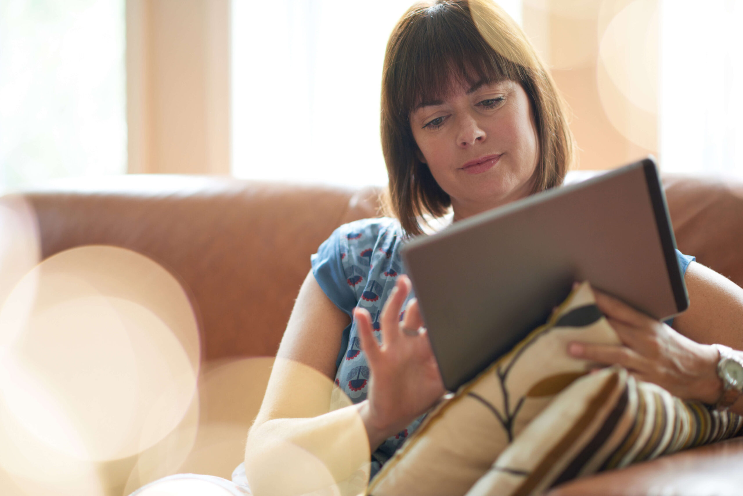 middle age woman on a sofa using her tablet