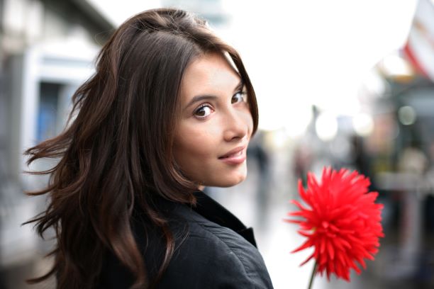 portrait of a woman with a flower locking over her shoulder&nbsp;
