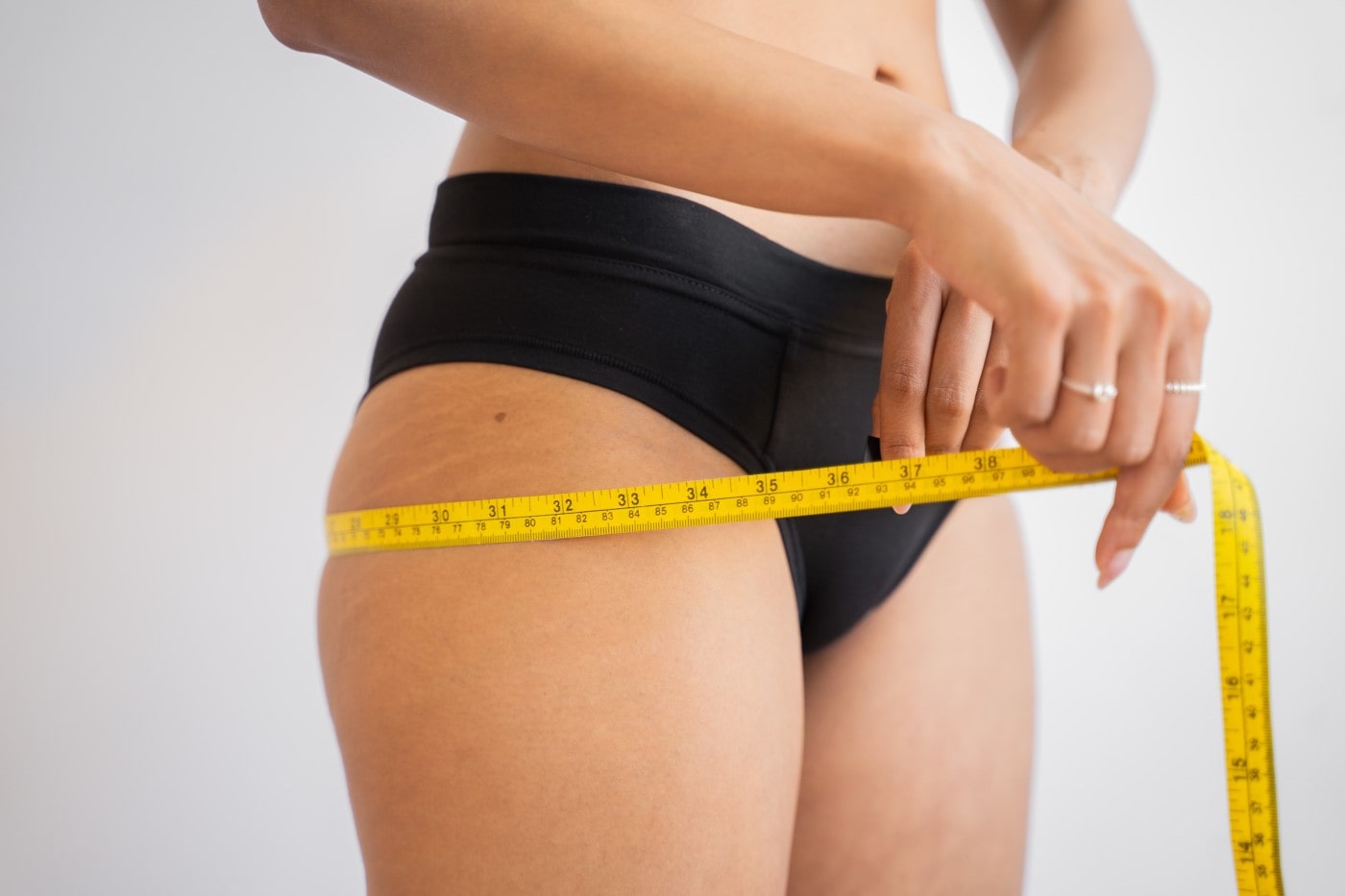 woman measuring her hips with a tape measure