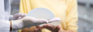 person holding a breast implant with one hand