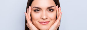 face of a smiling woman holding her face with two hands